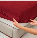Maroon terry mattress protector deep pocket being fitted to a mattress