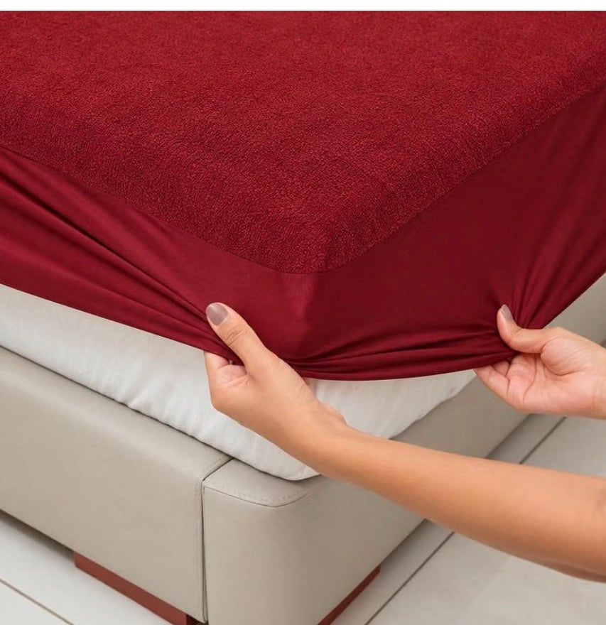 Maroon terry mattress protector deep pocket being fitted to a mattress