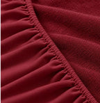 Close-up of maroon terry mattress protector elastic edge and terry fabric