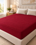 Maroon terry waterproof mattress protector fitted on a bed