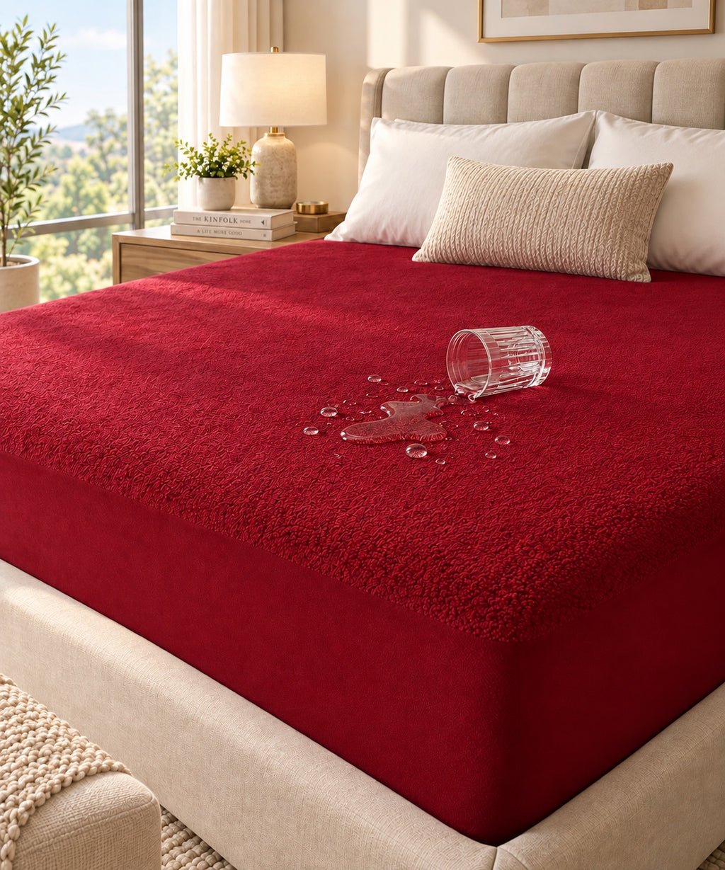 Maroon terry waterproof mattress protector with spilled water beading on the surface