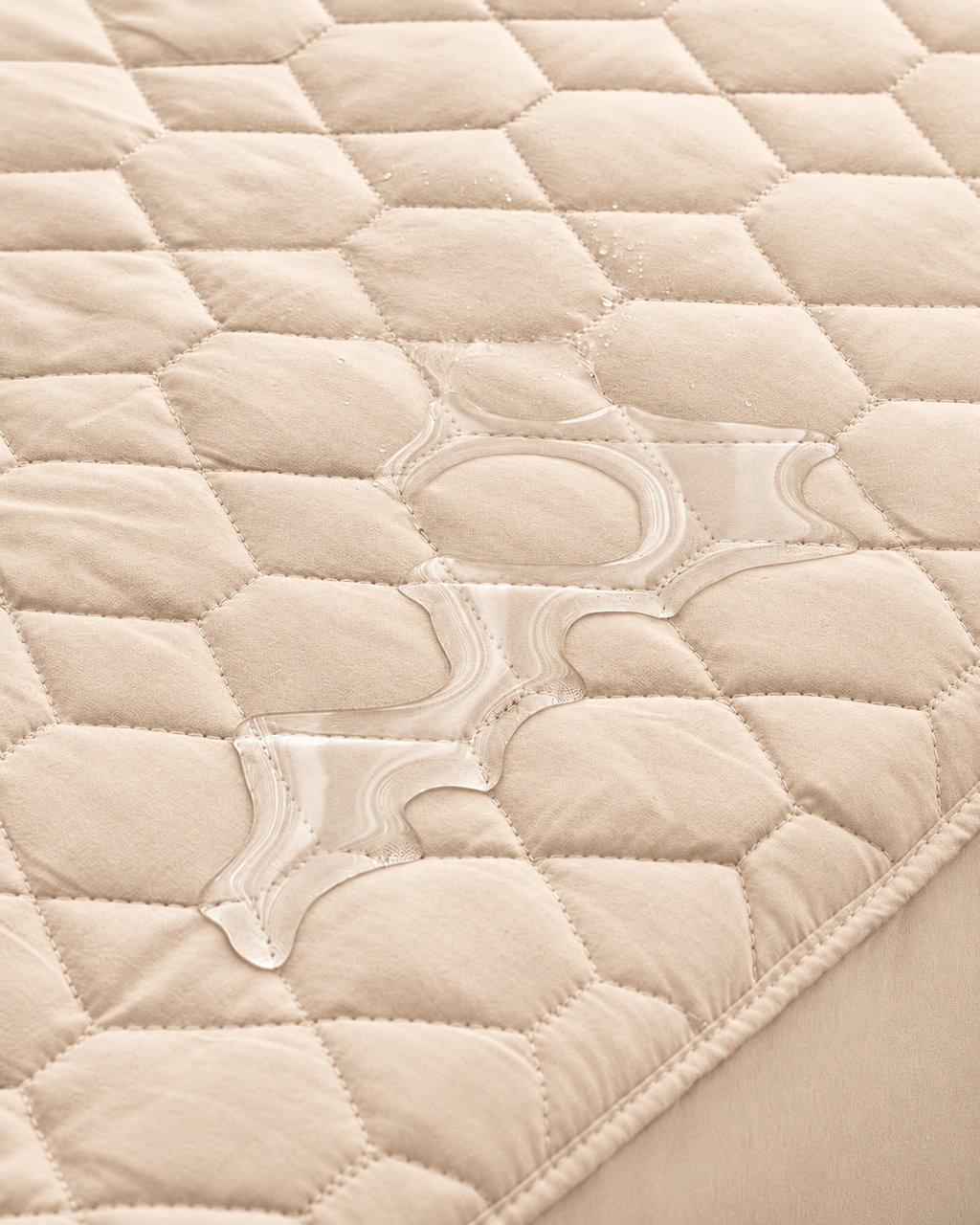 Beige quilted mattress protector – water close-up