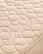 Beige quilted mattress protector – water close-up