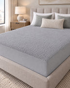 Grey Terry Mattress Protector fitted on a bed in a neutral bedroom