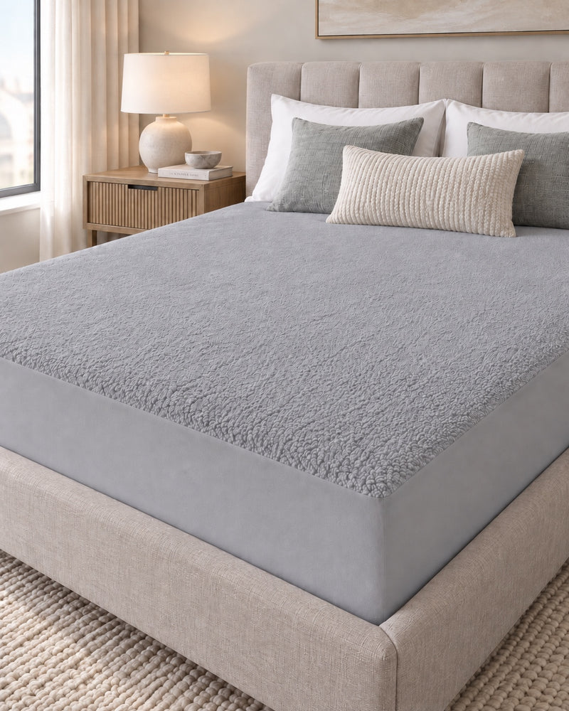 Grey Terry Mattress Protector fitted on a bed in a neutral bedroom