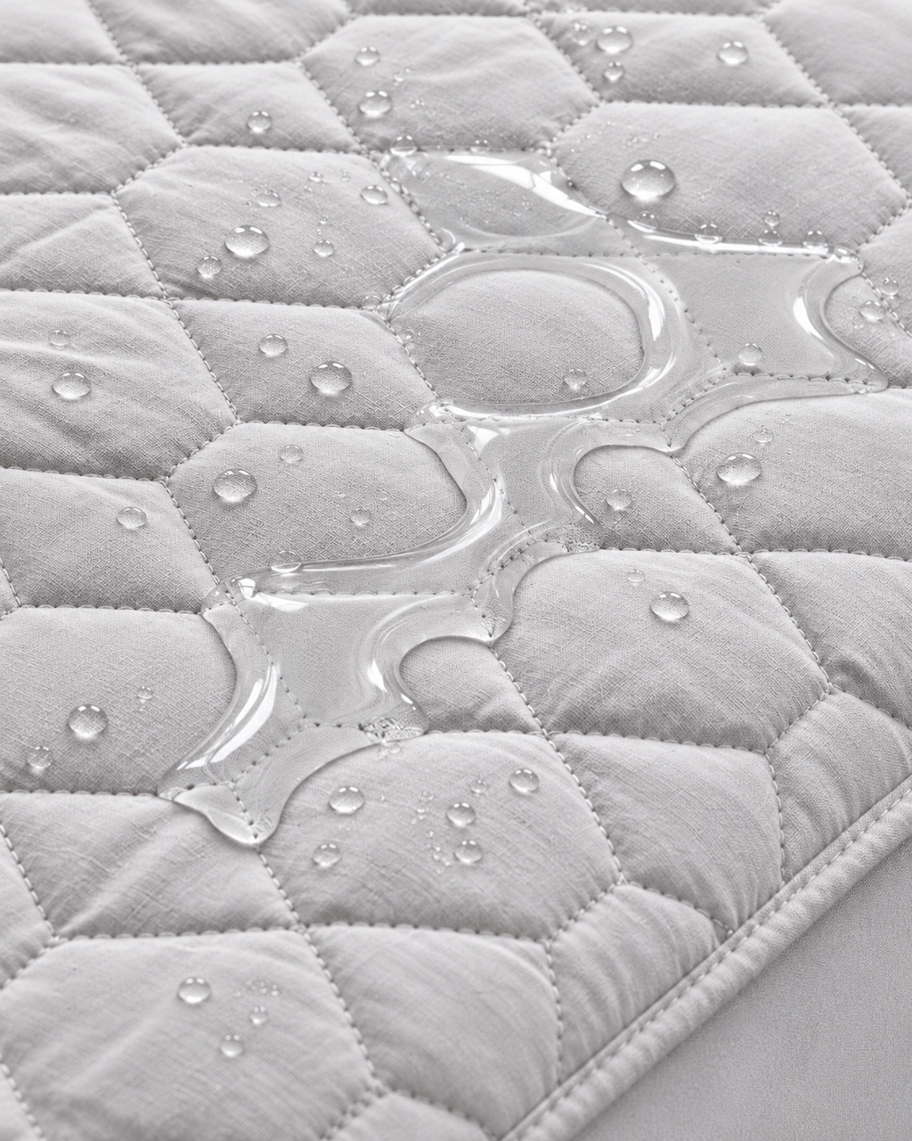 Water on grey quilted mattress protector close-up