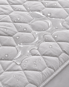 Water on grey quilted mattress protector close-up