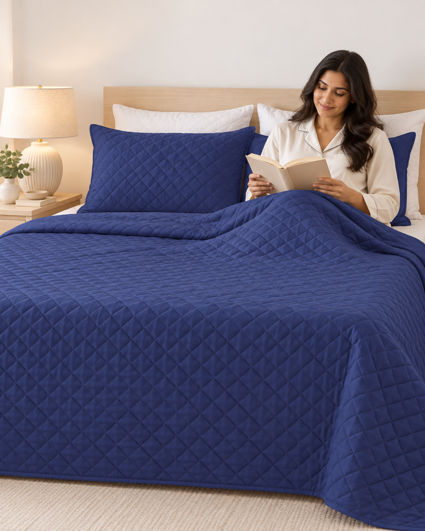 A woman relaxing on a bed with a navy quilted dohar